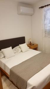 a bedroom with a large bed with white sheets and a window at Casa Dos Santos Alojamento - Guest House in Geres