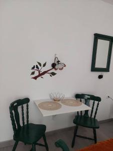 een witte tafel met twee groene stoelen en een spiegel bij apartman Vrdničak 1 in Vrdnik