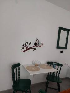 een witte tafel met twee groene stoelen en een spiegel bij apartman Vrdničak 1 in Vrdnik