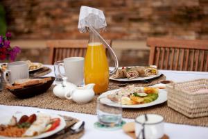 a table with plates of food and a bottle of orange juice at Ewange - A Casa Mia in Kampala