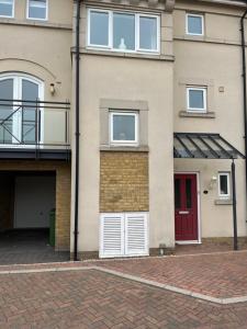 una casa con una puerta roja y un garaje en Peterborough, Hampton Vale Lakeside En-Suite Large Double bedroom with great modern facilities, en Peterborough