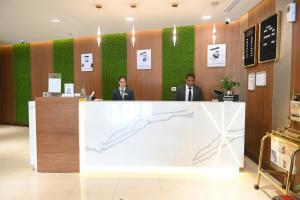 two men standing at a counter in a lobby at Smana Hotel Al Raffa in Dubai