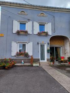 ein blaues Haus mit weißen Fensterläden und Blumen in der Unterkunft Chambre d'Emma 