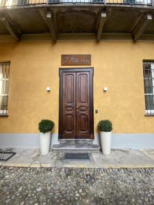 a building with a wooden door with two plants in front at 7 Seven in Biella