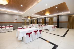 a banquet hall with white tables and red chairs at Poornima Regency in Bangalore