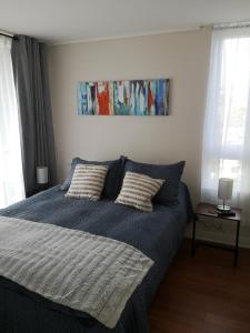una camera da letto con un letto blu con due cuscini di Tranquilo y Acogedor departamento en Con Con a Concón