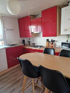 une cuisine avec des placards rouges et une table en bois avec des chaises dans l'établissement Au cœur du champagne logement privatif (70 m2), à Épernay