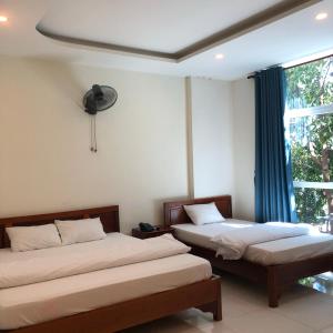 2 Betten in einem Zimmer mit Fenster in der Unterkunft Nhà nghỉ Linh Quân in Vũng Tàu