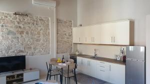 a kitchen with white cabinets and a table and a refrigerator at Christos Katerina House in Pythagoreio