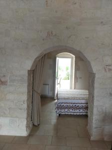 una camera con arco, letto e finestra di I trulli di Nonno Battista a Locorotondo