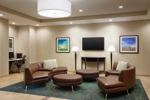 Candlewood Suites Valdosta Mall, an IHG Hotel في فلدوستا: غرفة انتظار مع كراسي وتلفزيون بشاشة مسطحة
