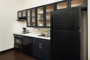 a kitchen with black cabinets and a black refrigerator at Candlewood Suites Valdosta Mall, an IHG Hotel in Valdosta