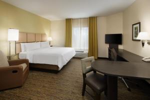 Candlewood Suites Valdosta Mall, an IHG Hotel في فلدوستا: غرفة في الفندق بسرير ومكتب وطاولة