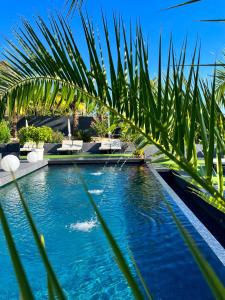 a pool with blue water and palm trees at Les Suites du Lac in Aix-les-Bains