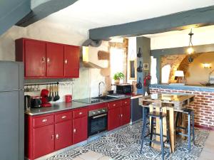 a kitchen with red cabinets and a table in it at Gîte l'Echappée belle in Castelnau-Pégayrols