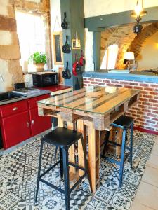 a kitchen with a wooden table and two stools at Gîte l'Echappée belle in Castelnau-Pégayrols