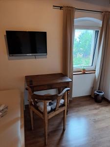 a room with a tv and a chair and a window at Pension Müllers Mühle in Großenhain