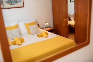 una camera da letto con letto, cuscini gialli e specchio di Apartments House Risika a Risika