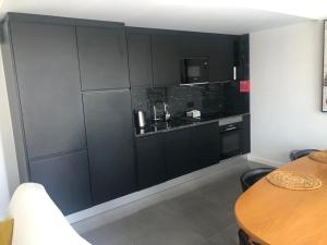 uma cozinha com armários pretos e uma mesa de madeira em Apartamento Deluxe AM em Faro