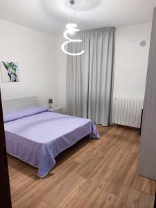 een slaapkamer met een bed met paarse lakens en een kroonluchter bij Alice apartment in Salemi