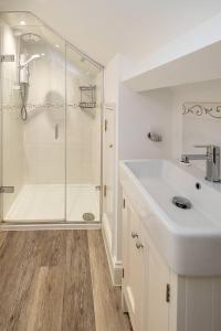 a white bathroom with a shower and a sink at The Haven at Coastguard Court - Aldeburgh Coastal Cottages in Aldeburgh