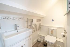 a white bathroom with a sink and a toilet at The Haven at Coastguard Court - Aldeburgh Coastal Cottages in Aldeburgh