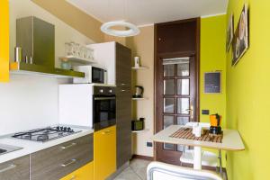 eine Küche mit grünen und gelben Wänden und einem Tisch in der Unterkunft BLUE LAKE ARONA - cozy apartment in city center in Arona