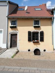 una casa amarilla con dos ventanas y una puerta en Ferienwohnung, Charmantes Bauernhaus, Ferienhaus, en Saarlouis