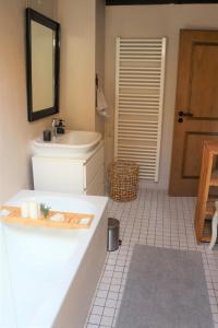ein Badezimmer mit einer Badewanne, einem Waschbecken und einem Spiegel in der Unterkunft Ferienwohnung, Charmantes Bauernhaus, Ferienhaus in Saarlouis