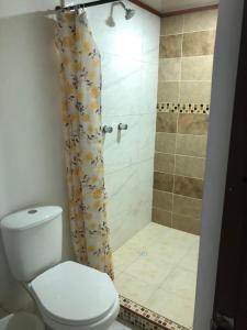 y baño con ducha, aseo y cortina de ducha. en montecarlos hotel, en Ibagué