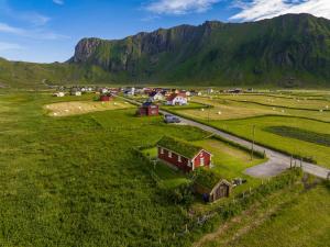 a village in a field with a mountain in the background at Unstad cabin with seaview in Unstad