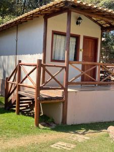 Casa pequeña con porche de madera y puerta en Pousada Villa Recanto dos Lagos, en Brumadinho