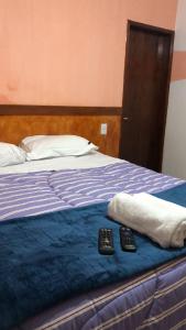 a bed with two remote controls sitting on it at Pousada Sitio Roda D'Água Mairinque in Mairinque