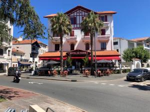 a street with a building with tables and palm trees at Superbe appartement T3 au centre plage .Parking in Hendaye