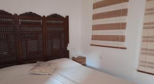 a bed with a wooden headboard and a pillow on it at Sea view Penthouse with beautiful Terrace - Casa Verdi Jayanti in Lido di Ostia