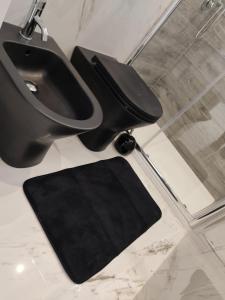 baño con aseo negro y alfombra negra en Black & White, en Pietra Montecorvino