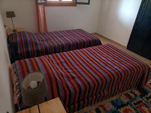 a small bedroom with a bed with a striped blanket at Dar Albatros in Sidi Kaouki