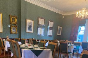 een eetkamer met tafels en stoelen en een kroonluchter bij Lovat Arms Hotel in Beauly