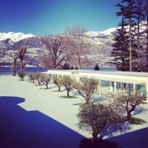 a building with snow covered mountains in the background at Seven Park Hotel Lake Como - Adults Only in Colico