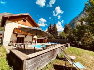 een huis met een terras met een parasol en een zwembad bij Chalet Les Ecrins in Vénosc