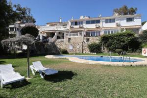 duas cadeiras e um guarda-sol junto a uma piscina em Quaint 2 Bedroom Townhouse with Pool close to Sea! em Benalmádena