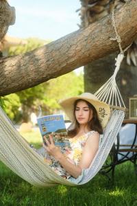 a woman laying in a hammock reading a book at Heliotopos in Skala Eresou