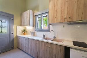 a kitchen with wooden cabinets and a sink and a window at Heliotopos in Skala Eresou