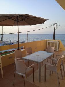 eine Terrasse mit einem Tisch, Stühlen und einem Sonnenschirm in der Unterkunft Villa Constantsia in Káto Ássos