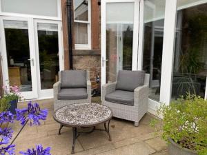 two chairs and a coffee table on a patio at Braid Rd Stunning Villa in Edinburgh