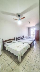 a bedroom with two beds and a ceiling fan at POUSADA POLONINI - Localização ótima in Piúma