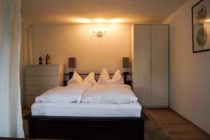 1 dormitorio con 1 cama con almohadas blancas en Wohlfühlen am Großen Goitzschesee inkl. Netflix, en Holzweißig