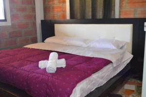 Una cama con dos toallas enrolladas. en Akasha Encuentro Finca cerca a Medellín., en Guarne