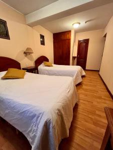 a hotel room with two beds and wooden floors at Hotel Vilandre in Cusco