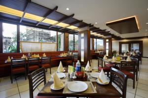 a restaurant with wooden tables and chairs and windows at Hotel Express Towers in Vadodara